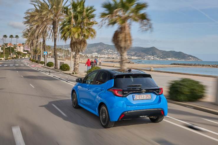 un auto in strada con il mare sullo sfondo